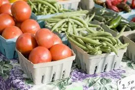 Tomatoes and green beans in baskets for purchase.