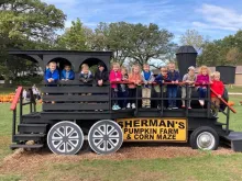 Kids smiling for photo op on train made of wood.