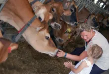 Women and child petting dairy cow during a tour.