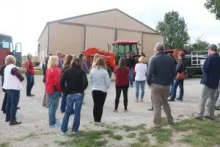 Group of people standing around tractor for presentation.