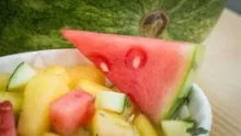 Watermelon and other fruits and vegetables cut up in a bowl.