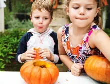 Two children carving small pumpkins.