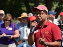 Ajay Nair speaking to a group of people in a field.