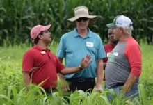 Ajay Nair speaking to a group of people in a field.